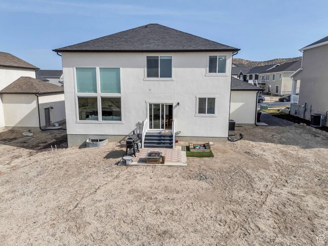 Back of property with a patio, stucco siding, cooling unit, and a shingled roof | Image 39