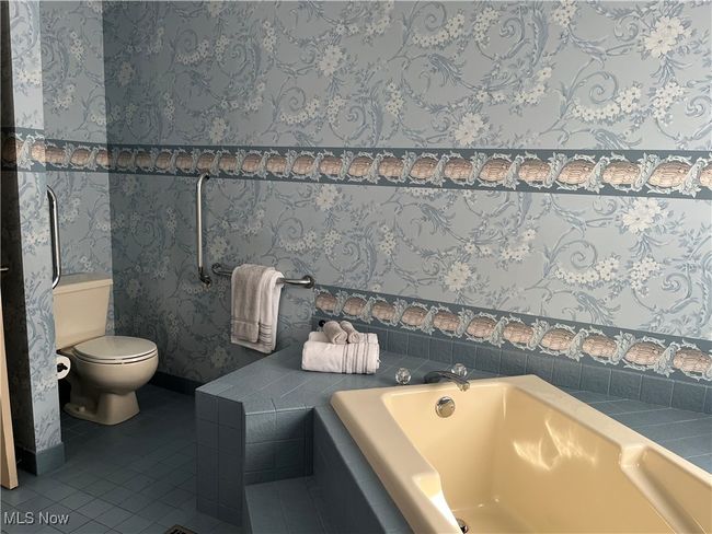 Bathroom with tile patterned flooring, tiled tub, and toilet | Image 23