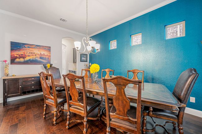 Dining space with a chandelier, baseboards, wood finished floors, and ornamental molding | Image 7