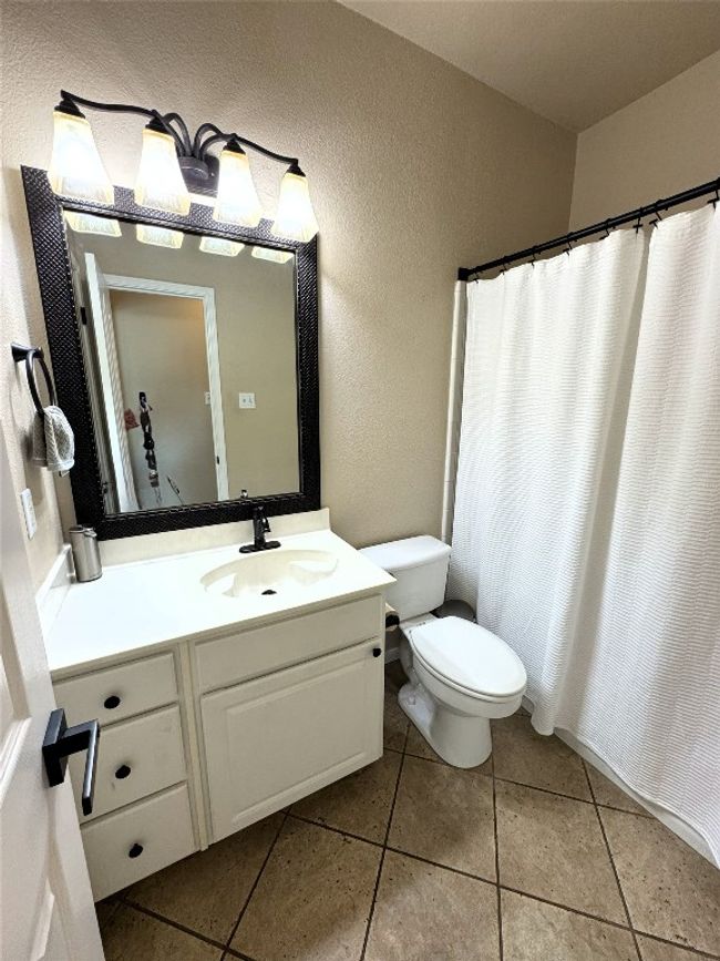 Downstairs bathroom featuring vanity, a textured wall, tile patterned flooring, and curtained shower. | Image 13
