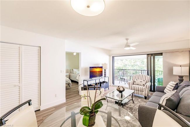 Living area with light wood-style flooring, a ceiling fan, and baseboards | Image 6