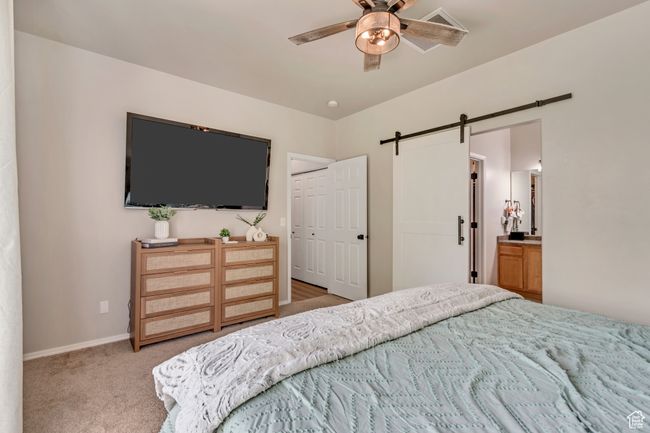 Bedroom featuring carpet floors, a closet, baseboards, a barn door, and a ceiling fan | Image 9