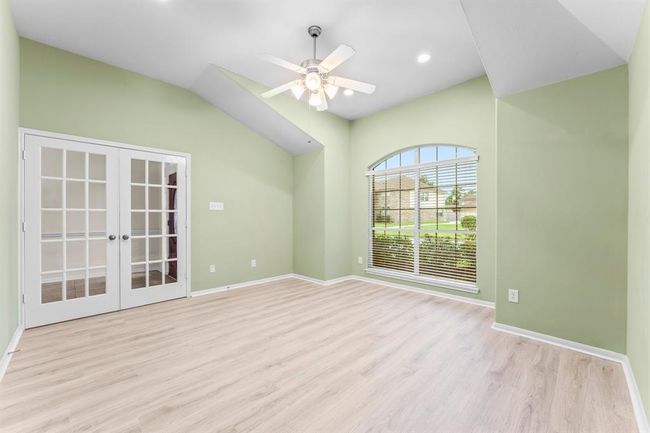 Bathed in natural light, the study features high vaulted ceilings, recessed lighting, and a large arched window with peaceful views of the front yard. French doors add both charm and privacy, making this space as functional as it is beautiful. | Image 4