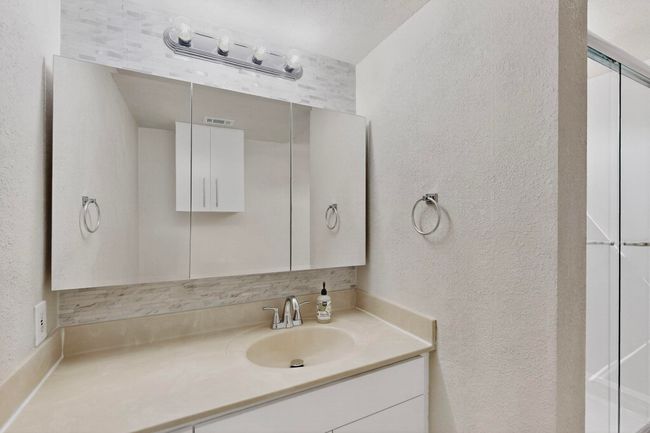 Bathroom with a textured wall and vanity | Image 26