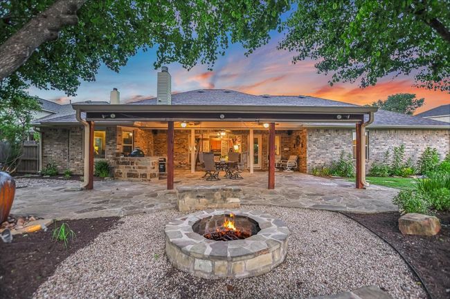 Back of house at dusk with a fire pit, a patio area, a chimney, ceiling fan, and brick siding | Image 35