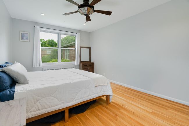 Bedroom featuring wood finished floors, baseboards, radiator heating unit, recessed lighting, and a ceiling fan | Image 9