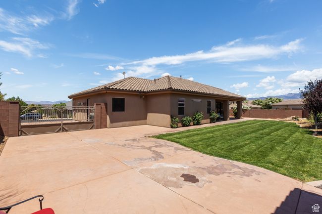 Rear view of property with stucco siding, a mountain view, a patio, a tile roof, and a gate | Image 7