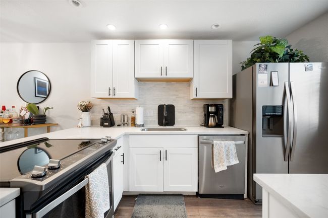 Kitchen featuring stainless steel appliances, decorative backsplash, light countertops, wood finished floors, and recessed lighting | Image 5