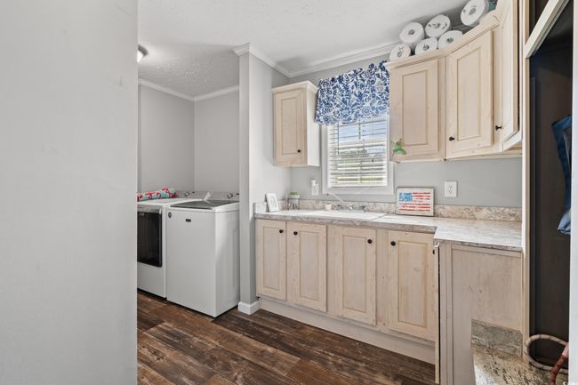 Laundry area featuring washing machine and clothes dryer, crown molding, dark wood finished floors, cabinet space, and a textured ceiling | Image 18