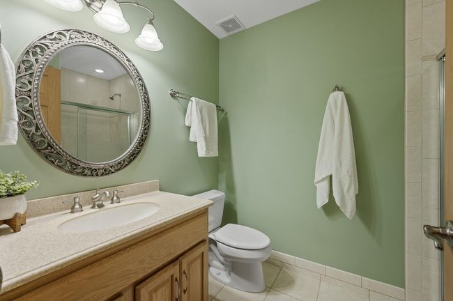 Lower bathroom with ceramic tile floors, glass door and tiled shower & designer mirror is perfect for family and guests. | Image 34