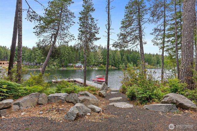 A thoughtfully landscaped path leading to the boat dock and a view of Tee Lake from the future home site. The presence of full-time residents and new homes being built indicates a vibrant and desirable community. | Image 17