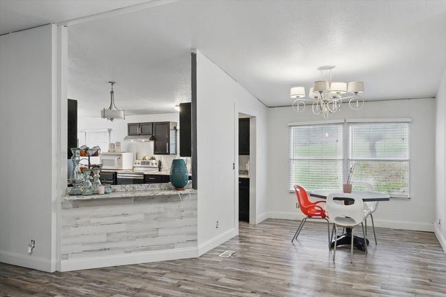 Dining room with baseboards, wood finished floors, and a notable chandelier | Image 5