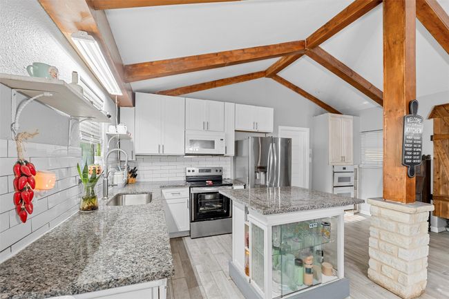 Kitchen featuring appliances with stainless steel finishes, a sink, and light stone countertops | Image 4