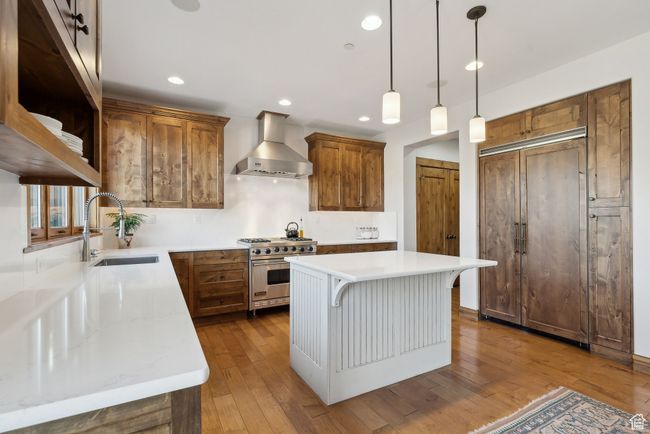 Kitchen featuring wall chimney range hood, brown cabinetry, designer stove, and a sink | Image 9