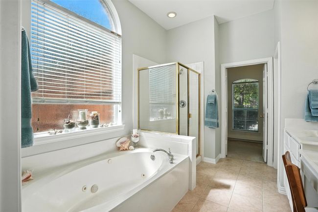 Bathroom featuring a jetted tub, a shower stall, vanity, and tile patterned flooring | Image 19