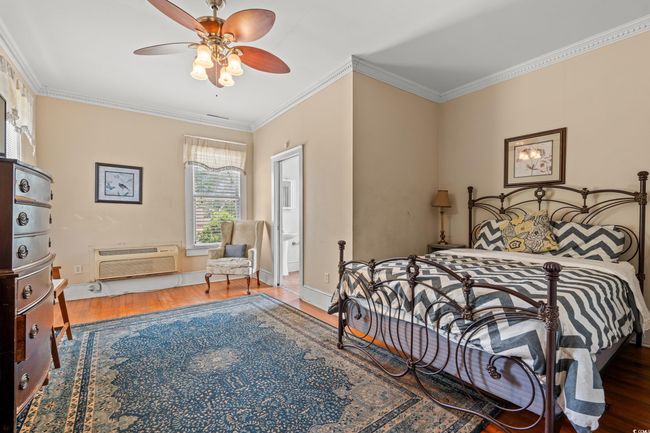 Bedroom featuring wood finished floors, crown molding, an AC wall unit, and ceiling fan | Image 24