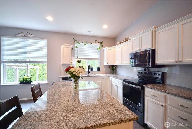 Kitchen has white mill cabinets granite counter tops, full tile backsplash, huge island with breakfast bar. Walk-in pantry. | Image 10
