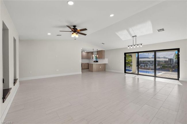 Unfurnished living room featuring light tile patterned flooring, rail lighting, ceiling fan, and lofted ceiling | Image 15