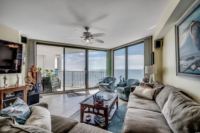 Living room featuring a wall of windows, a water view, ceiling fan, healthy amount of natural light, and tile patterned floors | Image 9