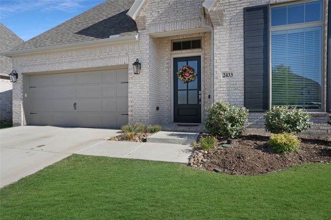 Property entrance with brick siding, a garage, driveway, and a shingled roof | Image 24