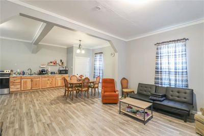 Living room featuring sink, ornamental molding, light hardwood / wood-style flooring, and an inviting chandelier | Image 3