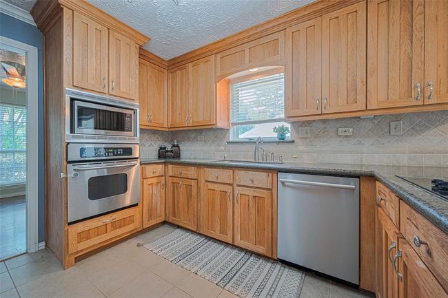 The kitchen features granite countertops, undermount lighting, and stainless appliances. | Image 10