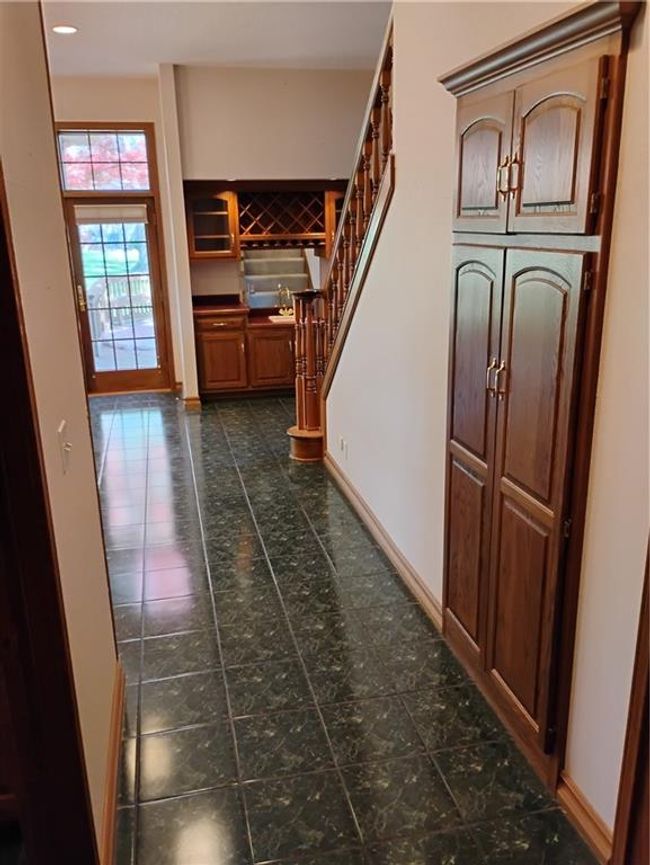 Kitchen hallway featuring recessed lighting, Storage pantry, dark tile patterned floors, stairway, and oak baseboards | Image 40