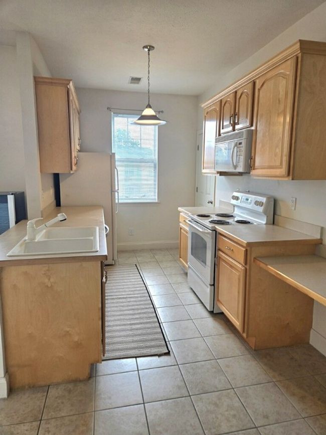 The kitchen features a window, desk area, and pantry. | Image 8