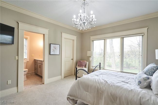 Bedroom #4 featuring crown molding, a notable chandelier, multiple windows, and newer carpet. It has has a private bath and a walk in closet | Image 23