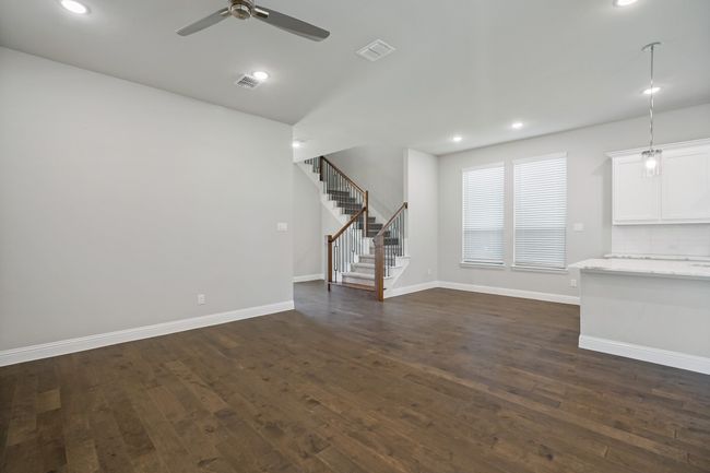 Unfurnished living room featuring dark wood finished floors, stairs, and visible vents | Image 7