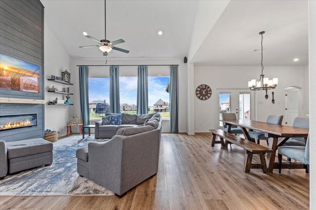 Living area featuring ceiling fan with notable chandelier, wood finished floors, a large fireplace, and recessed lighting | Image 9
