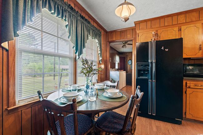 Dining room with wood walls, a ceiling fan, washing machine and dryer, light wood-style floors, and crown molding | Image 4