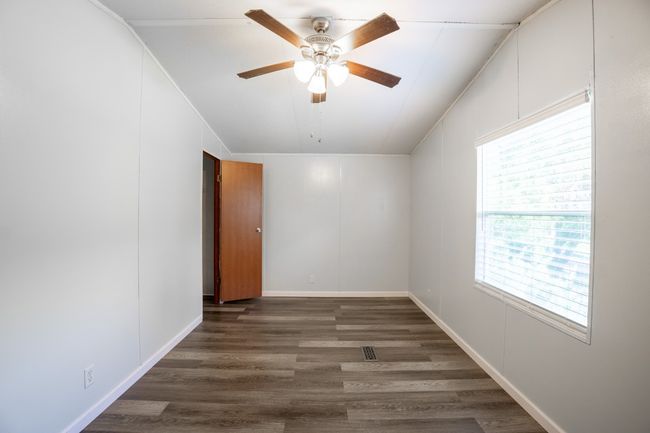 Unfurnished room featuring plenty of natural light, wood finished floors, a ceiling fan, and crown molding | Image 21