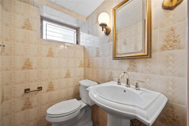 Half bath with tile walls, toilet, and a sink | Image 16