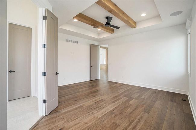Empty room with a tray ceiling, wood finished floors, baseboards, ceiling fan, and recessed lighting | Image 41