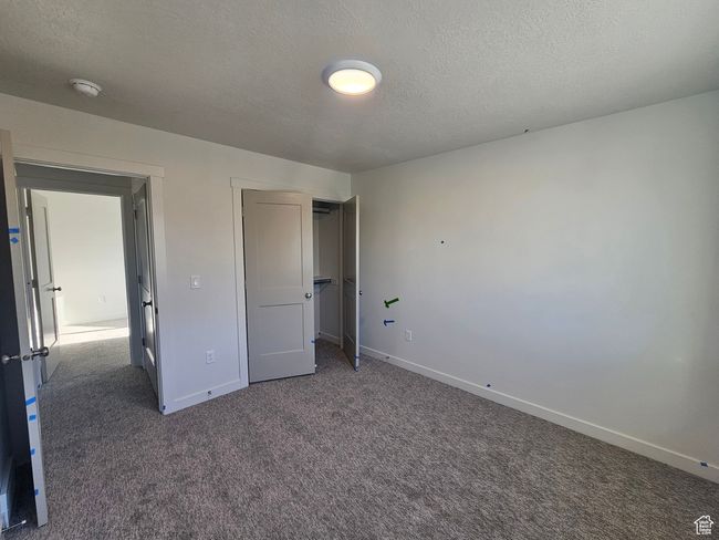 Unfurnished bedroom featuring carpet flooring, a textured ceiling, and a closet | Image 24