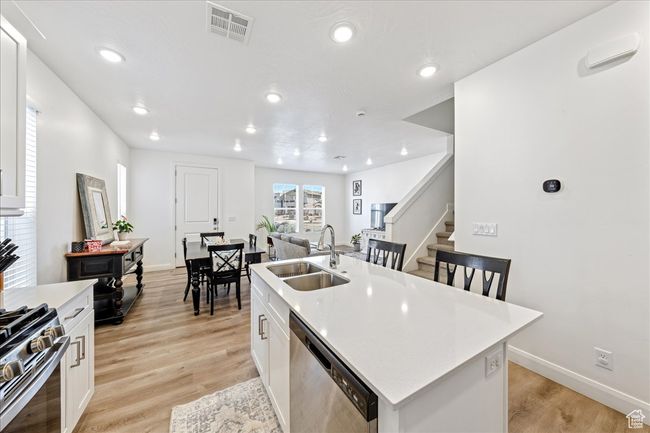Kitchen with appliances with stainless steel finishes, white cabinetry, a kitchen island with sink, light countertops, and recessed lighting | Image 9