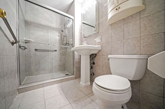 Full bath featuring toilet, a shower stall, tile walls, tile patterned floors, and ornate columns | Image 8