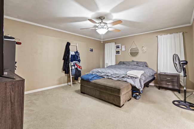Bedroom with light colored carpet, ceiling fan, and ornamental molding | Image 11