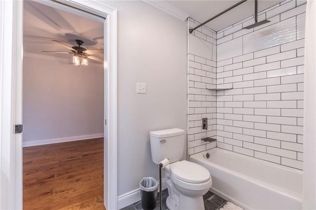 Bathroom featuring wood-type flooring, tiled shower / bath combo, toilet, and ornamental molding | Image 18