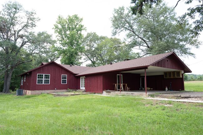 View of front of house featuring a carport, roof with shingles, a front yard, and board and batten siding | Image 33