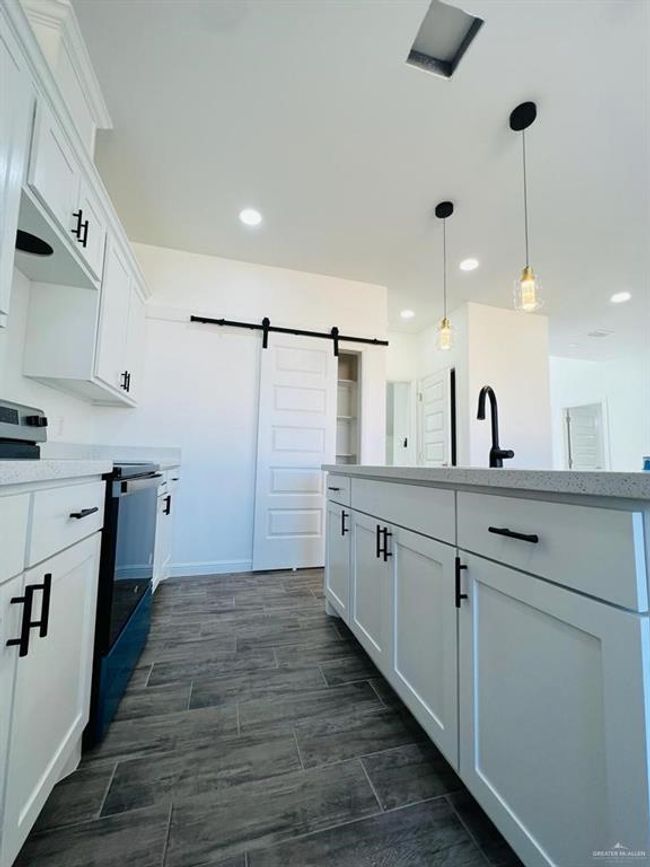 Kitchen featuring pendant lighting, electric range, a barn door, and white cabinets | Image 4