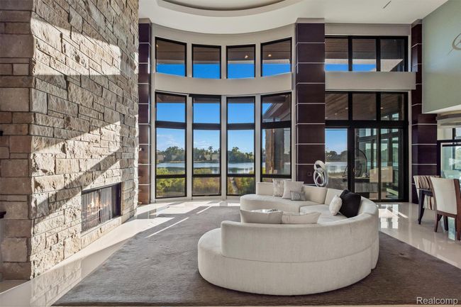Living room featuring a stone fireplace, a water view, a raised ceiling, and a high ceiling | Image 40