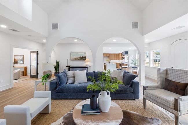 Living area featuring light wood-style floors, high vaulted ceiling, arched walkways, and recessed lighting | Image 22