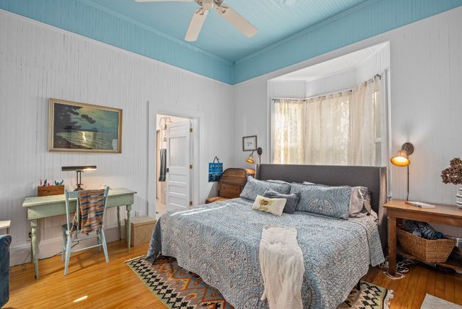 Bedroom with wood-type flooring, an office area, a ceiling fan, and connected bathroom | Image 15