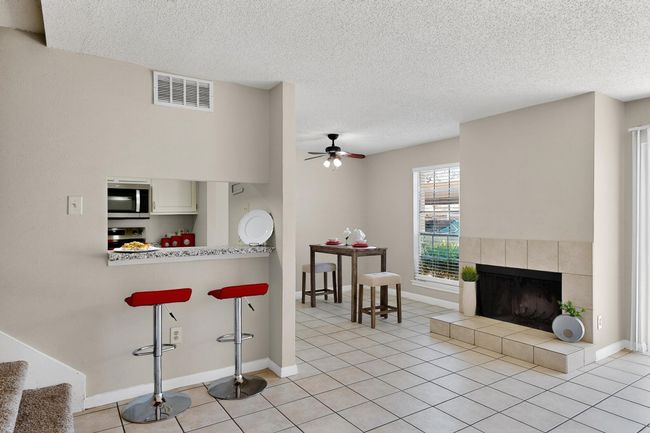 Kitchen with stainless steel microwave, a kitchen breakfast bar, a ceiling fan, light tile patterned flooring, and a textured ceiling | Image 7