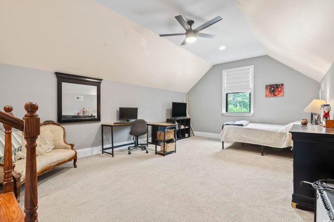 Bedroom featuring an office area, light carpet, vaulted ceiling, a ceiling fan, and baseboards | Image 25