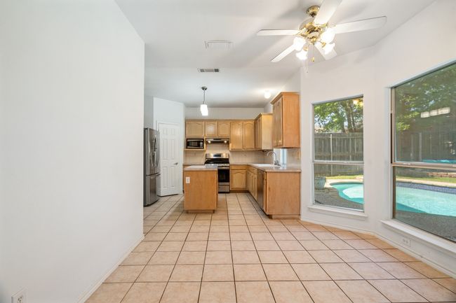 Kitchen featuring light tile patterned floors, under cabinet range hood, visible vents, appliances with stainless steel finishes, and a sink | Image 37