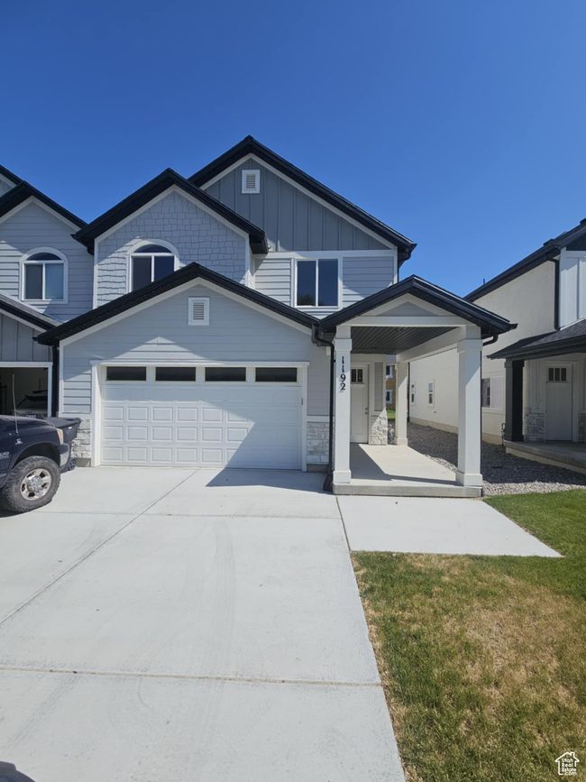View of front of home featuring driveway, covered porch, an attached garage, board and batten siding, and a front lawn | Image 11