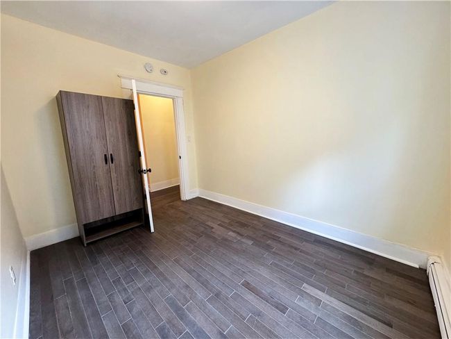 Empty room with dark wood-type flooring and baseboard heating | Image 12